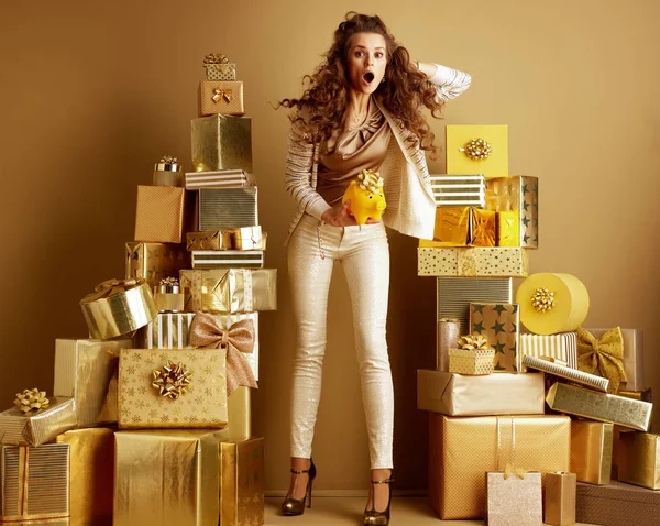 Шокированная покупательница держит желтую копилку с золотым бантом — стоковое фото