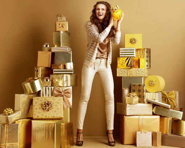 Glimlachend moderne vrouw schudden gele spaarvarken met gouden strik — Stockfoto