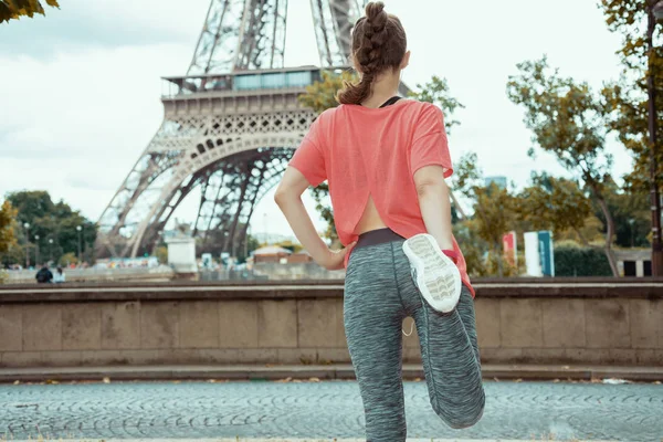 Mujer deportiva contra la vista despejada de la Torre Eiffel estiramiento — Foto de Stock