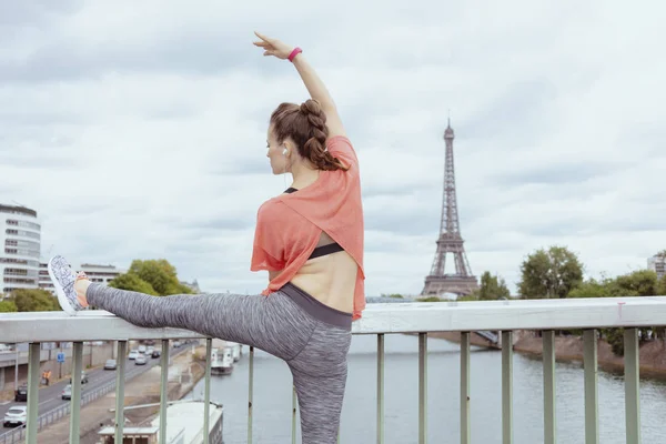 Mujer trotadora estirándose contra la torre Eiffel en París, Francia — Foto de Stock