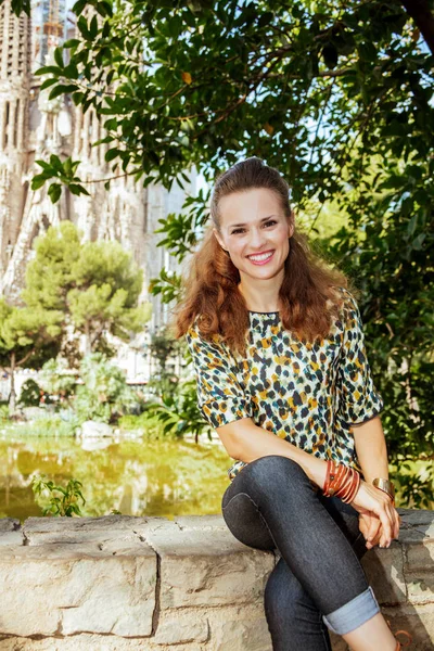 Lachende vrouw van de reiziger in Barcelona, Spanje zittend op de borstwering — Stockfoto