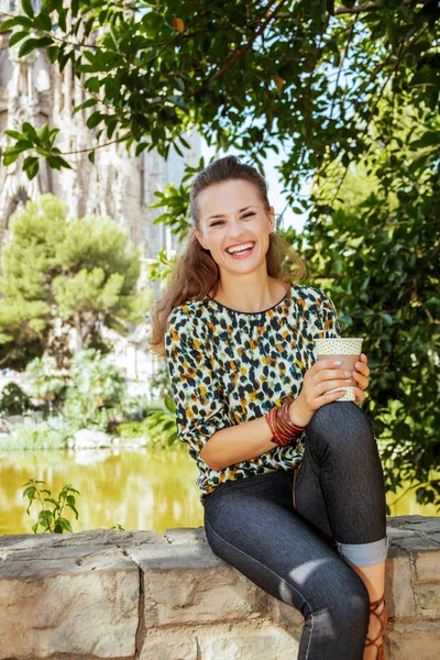 Sonriente solo turista mujer con taza de café sentado en parapeto —  Fotos de Stock