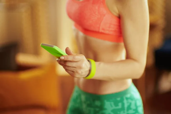 Nahaufnahme auf dem Smartphone in der Hand einer fitten Frau beim Ansehen fitter Videos — Stockfoto