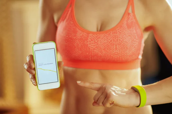Closeup on smartphone screen with fit app in hand of fit woman