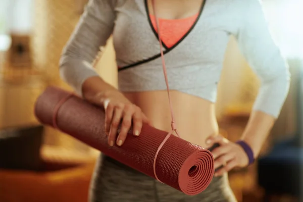 Primo piano sul tappeto fitness in mano alla donna sana a casa moderna — Foto Stock