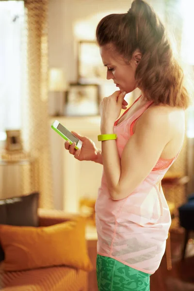 Mujer usando smartphone para ver streaming de fitness en internet —  Fotos de Stock