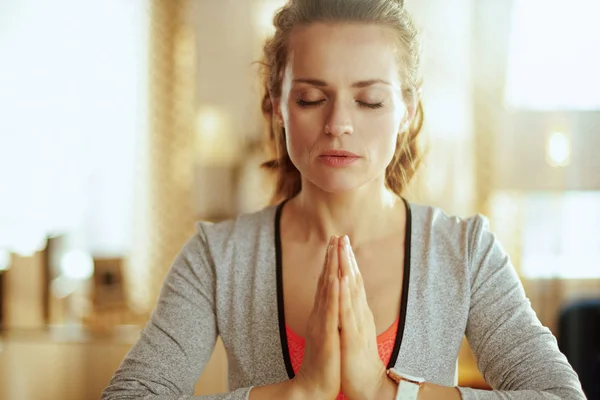 Расслабленная молодая спортивная женщина в современной гостиной медитирует — стоковое фото