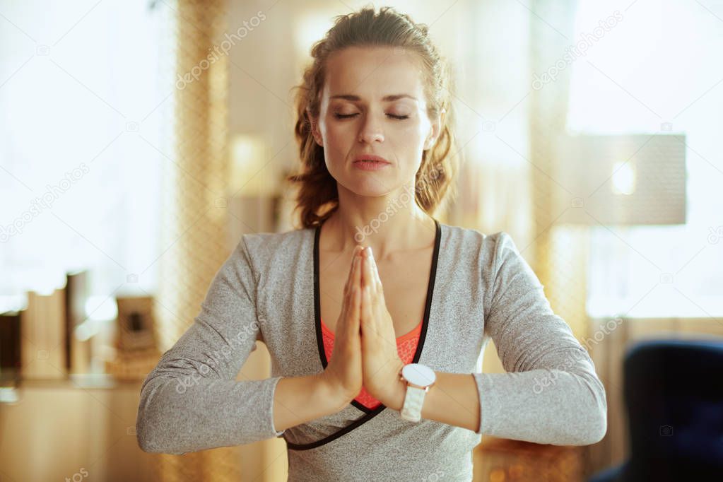 relaxed young sports woman in modern living room meditating