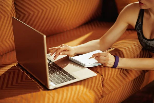 Closeup on woman with notepad and pen taking notes while using l — Stock Photo, Image