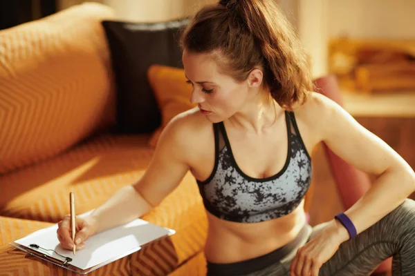日記とペンを建物のモダンな家のトレーニング スケジュール スポーツ服で女性に合う — ストック写真