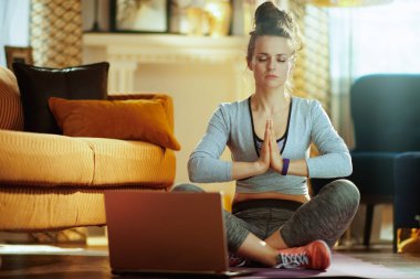 dizüstü bilgisayaronline yoga eğitim programı kullanarak meditasyon modern evde fitness giysileri rahat uygun spor kadın.
