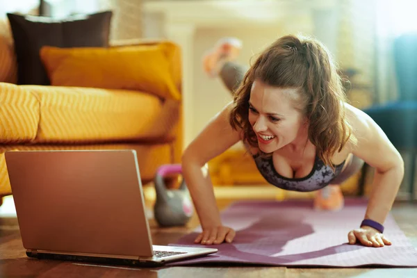 Lächelnde Gesunde Frau Fitnessklamotten Modernen Wohnzimmer Die Laptop Fitnessanleitungen Internet — Stockfoto