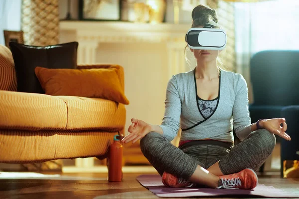 relaxed fit woman in sport clothes in the modern house in VR gear.