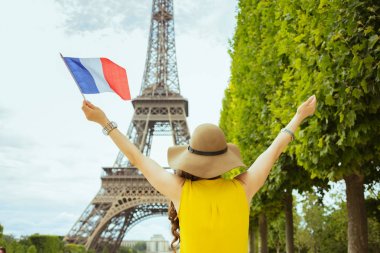 Paris, Fransa'da sevinen Fransız bayrağı ile sarı bluz ve şapka trendy kadın arkasından görüldü.