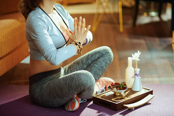 Closeup on active sports woman in sport clothes at modern home meditating.