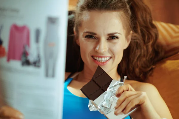 Portrait Happy Healthy Woman Fitness Clothes Laying Sofa Chocolate Bar — Stock Photo, Image