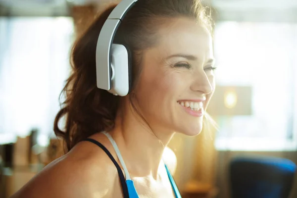 Mujer deportiva escuchando música con auriculares en casa moderna —  Fotos de Stock