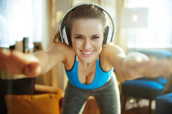 Mujer feliz en los auriculares en la sala de estar moderna estiramiento —  Fotos de Stock