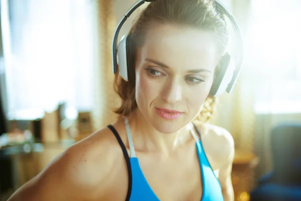 Jonge vrouw luisteren naar muziek met koptelefoon in modern huis — Stockfoto