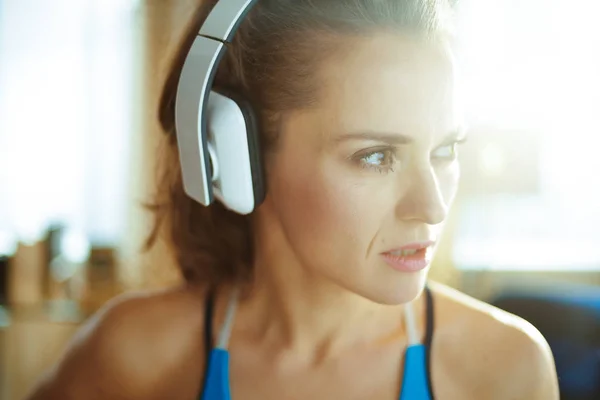 Ung kvinna lyssnar på musik med hörlurar i modernt hem — Stockfoto