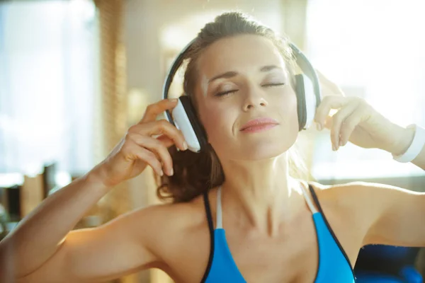 Mujer deportiva escuchando música con auriculares en el hogar moderno —  Fotos de Stock