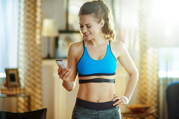 sports woman wearing heart rate monitor using smartphone