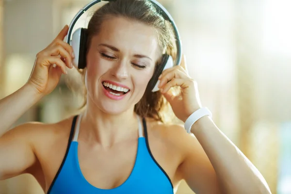 Szczęśliwa kobieta słucha muzyki ze słuchawkami w nowoczesnym domu — Zdjęcie stockowe