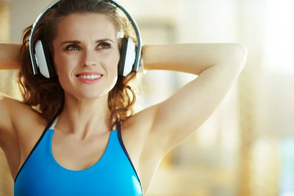 Gelukkige actieve sportvrouw die naar muziek luistert met een koptelefoon — Stockfoto