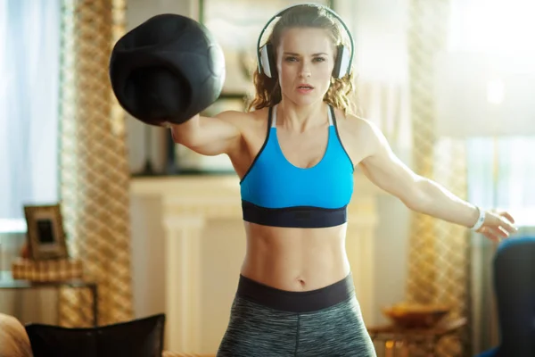 Sportvrouw in koptelefoon doet functionele trainingsoefeningen — Stockfoto