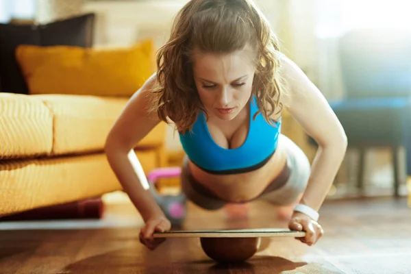 Vrouw in modern huis doen pushups met behulp van balance board — Stockfoto