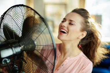 gülümseyen şık ev hanımı elektrikli zemin ayakta fan kullanarak