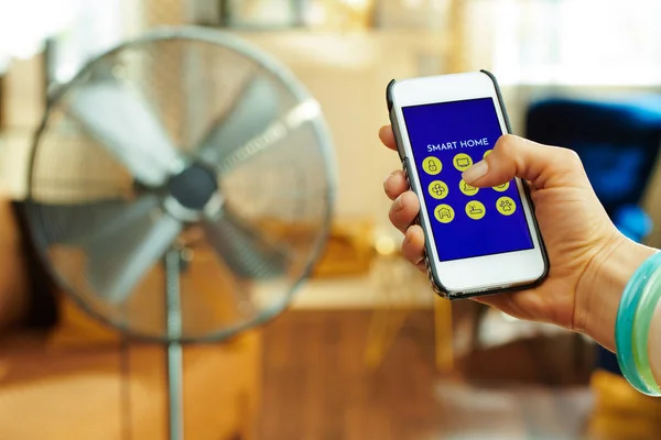 Smartphone con aplicación para el hogar inteligente en ventilador de control manual femenino — Foto de Stock