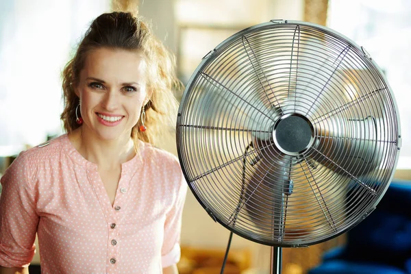 Gelukkig elegante vrouw in de buurt van metalen vloer staande fan — Stockfoto