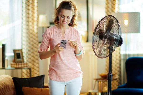 Felice donna moderna utilizzando l'app Smart Home per controllare il ventilatore — Foto Stock