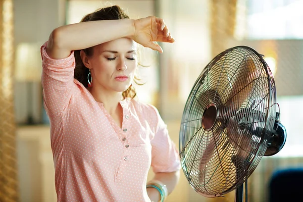 Woman exhausted from summer heat while standing in front of fan — Stock Photo, Image