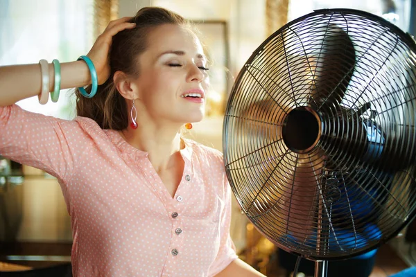 Nyugodt fiatal nő élvezi a friss levegőt előtt dolgozó ventilátor — Stock Fotó