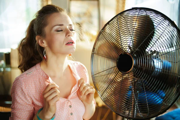 Mulher desfrutando de frescura perto fã sofrendo de calor de verão — Fotografia de Stock