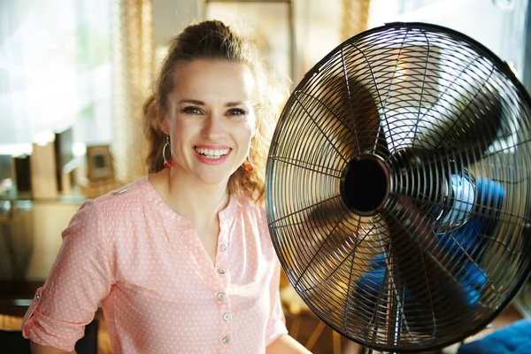 Sonriente elegante mujer enfriamiento abajo usando eléctrico metálico ventilador — Foto de Stock