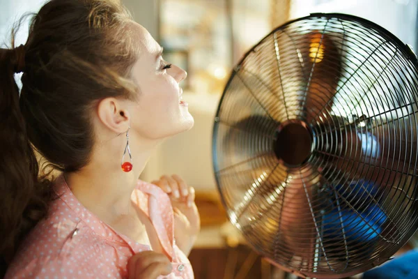 Розслаблена сучасна жінка насолоджується бризом перед робочим вентилятором — стокове фото