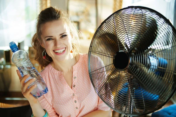 Vrouw met fles water genieten van frisse lucht in de voorkant van ventilator — Stockfoto