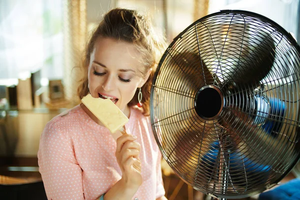 Háziasszony segítségével padlón álló ventilátor evés közben fagylaltot — Stock Fotó