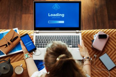modern kadın dizüstü bilgisayara cep telefonundan veri aktarımı