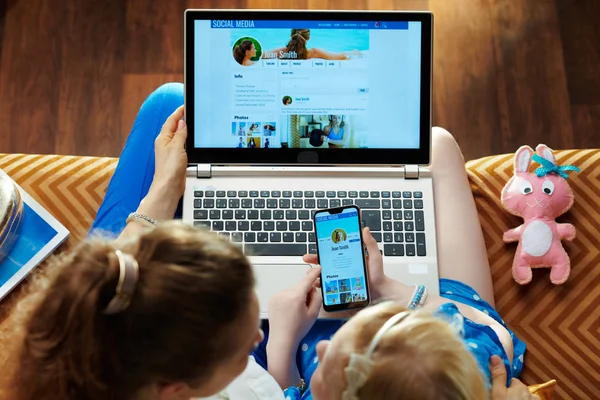 Matka i dziecko sprawdzanie mediów społecznościowych na laptopie i smartfonie — Zdjęcie stockowe