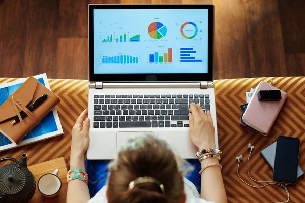 Trendy woman looking at graphs on laptop screen — Stock Photo, Image