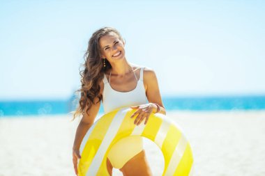 sahilde sarı şişme lifebuoy ile gülümseyen genç kadın