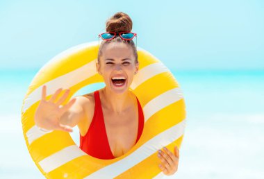 deniz kıyısında sarı şişme lifebuoy ile neşeli kadın