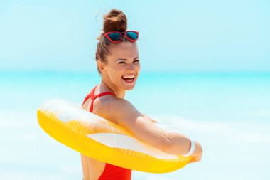 sarı şişme lifebuoy giyen plajda gülümseyen genç kadın