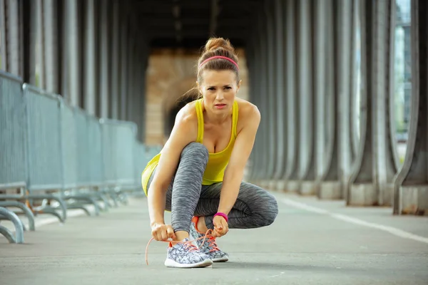 Woman on Pont de Bir-Hakeim bridge in Paris tying shoelaces — Stock Photo, Image