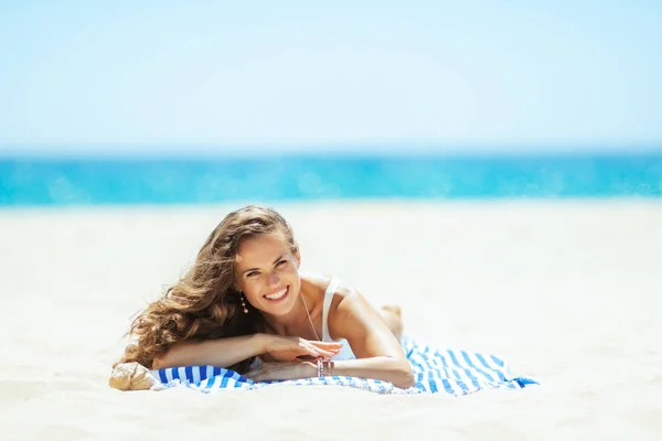 Felice donna sana sulla riva dell'oceano sdraiato su asciugamano a strisce — Foto Stock