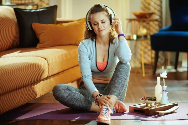 Mujer deportiva sana relajada escuchando música con auriculares —  Fotos de Stock